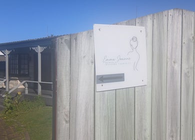 Entrance to Massage Em, Morrinsville, Waikato, NZ with a welcoming wooden sign and charming cottage.