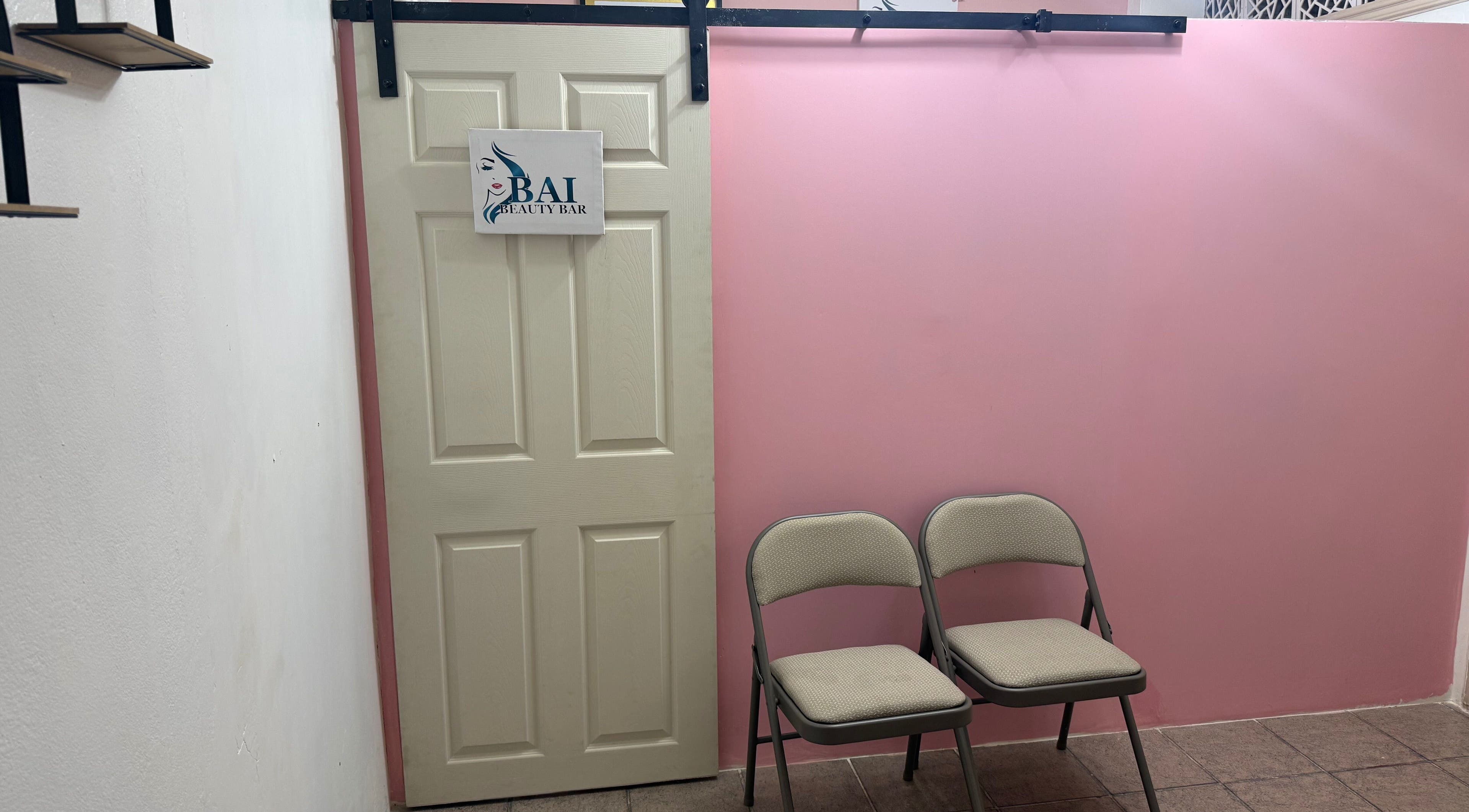 Entrance to Bai Beauty Bar in Kingston, St. Andrew Parish, JM with pink walls and waiting chairs.