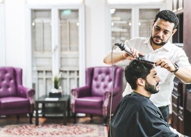 Barber styling hair at The British Barbers, Singapore, SG amidst elegant decor.