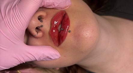 Close-up of lip piercings at Shine By S salon in Peterborough, England, GB, with aesthetic pink gloves.