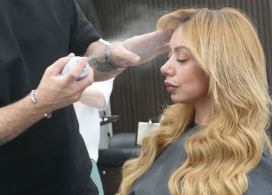 Stylist applying finishing spray to woman’s hair at Revive Hair Salon, Los Angeles, California, US.