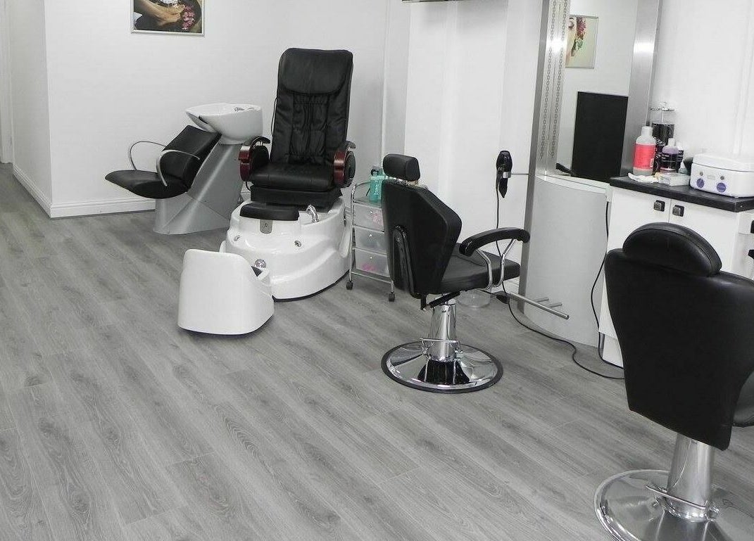 Modern salon interior at Glamour Beauticians, Manchester, England, GB, featuring sleek chairs and styling stations.