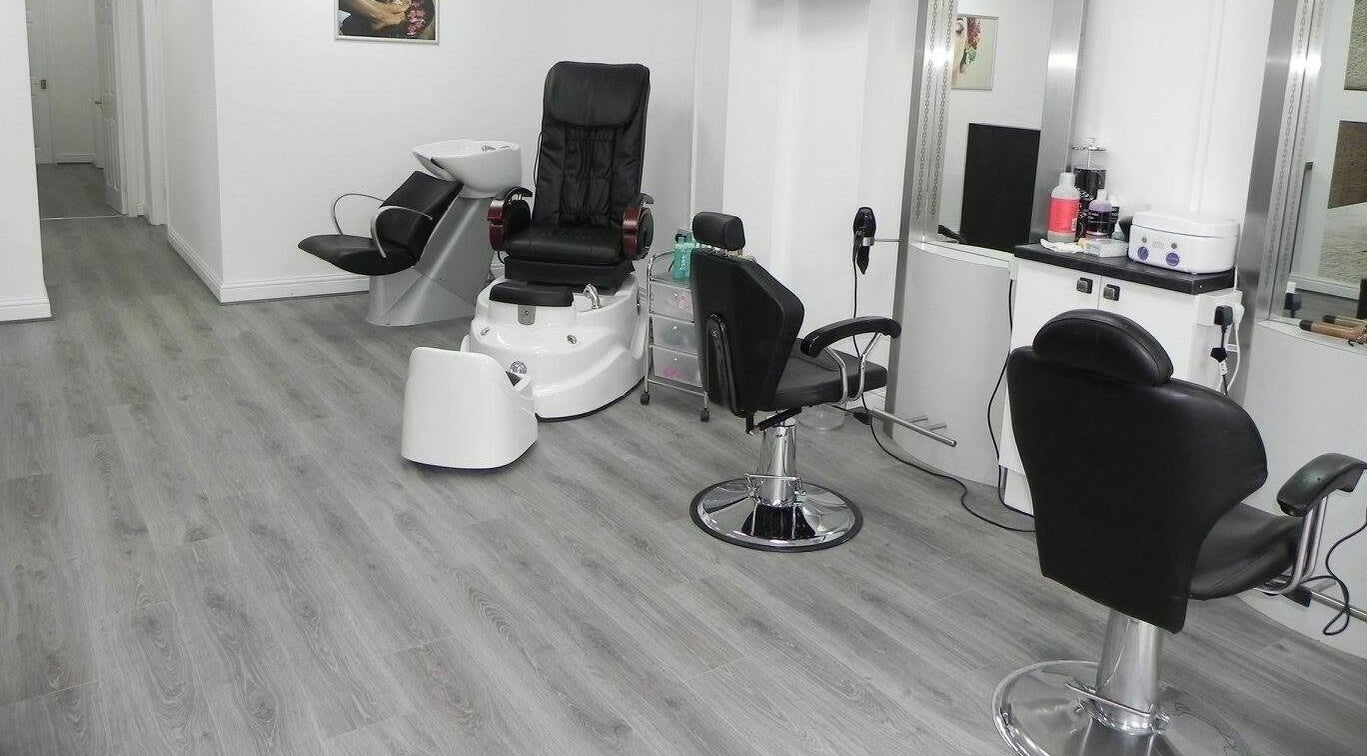 Modern salon interior at Glamour Beauticians, Manchester, England, GB, featuring sleek chairs and styling stations.