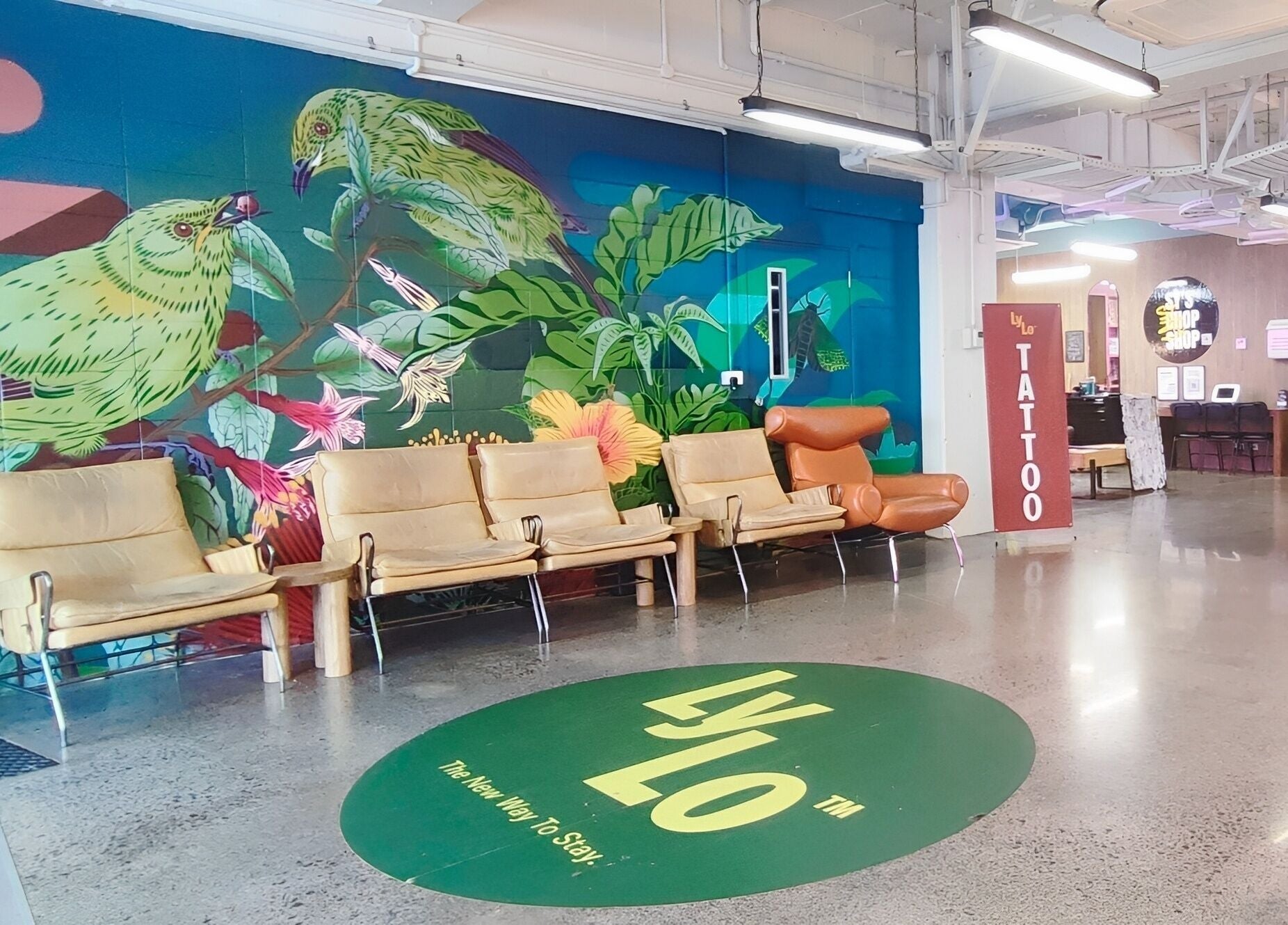 Colorful lounge at Sy's Chop Shop, Auckland, NZ featuring vibrant mural and cozy seating area.