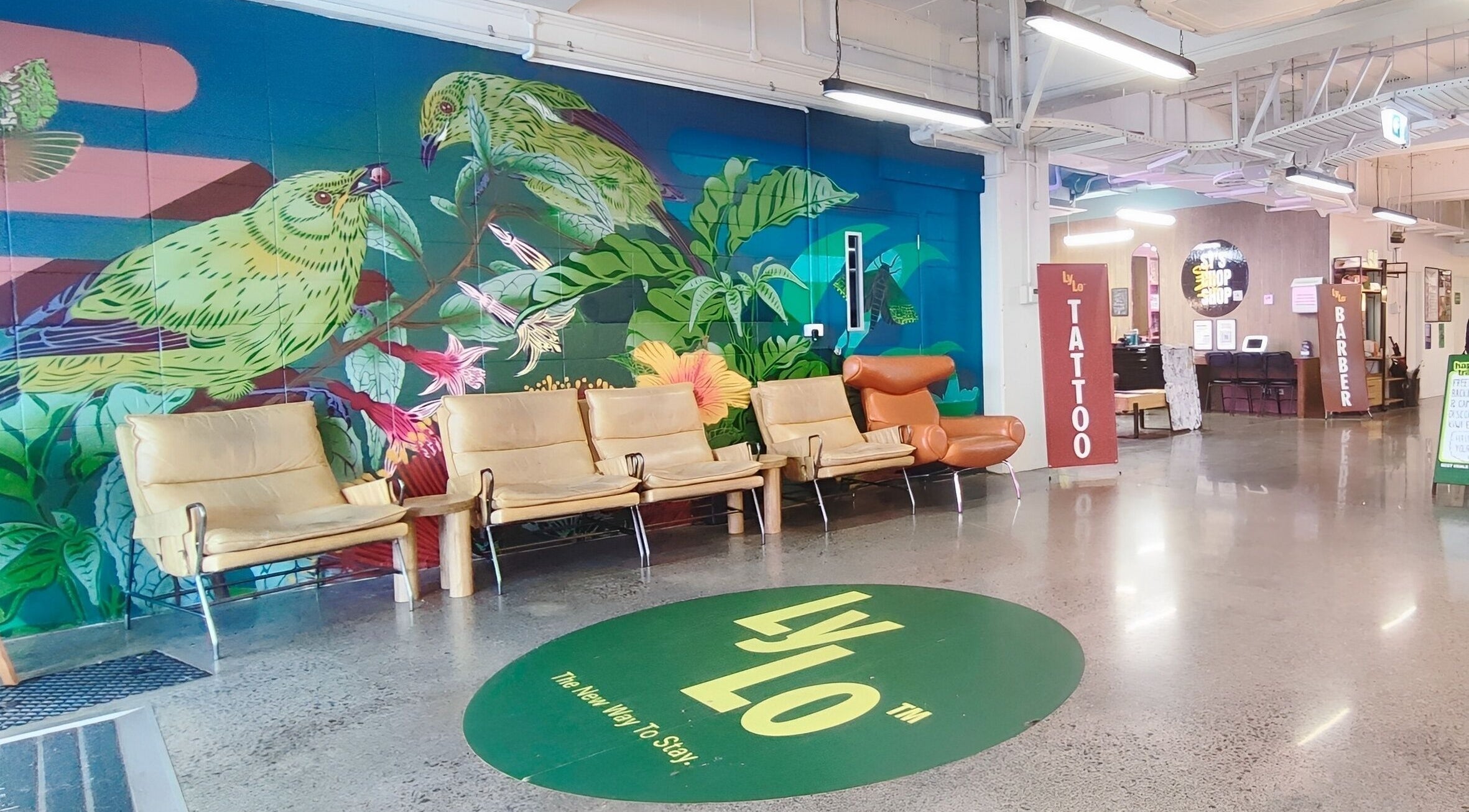 Colorful lounge at Sy's Chop Shop, Auckland, NZ featuring vibrant mural and cozy seating area.