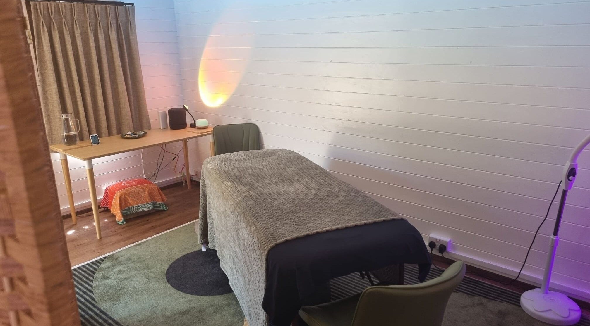 Calm therapy room at The Garden Retreat in Martlesham, England, GB featuring a massage table and ambient lighting.