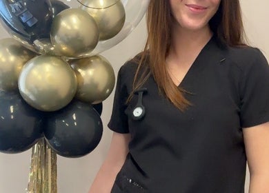 Staff member at CliniK Aesthetics, Irvine, Scotland, GB with decorative balloons, symbolizing a welcoming atmosphere.