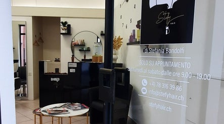 Ingresso accogliente del salone Stefy Hair a Locarno, Ticino, CH, con arredamento moderno e logo elegante.