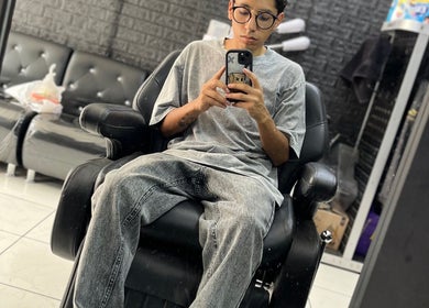 Interior moderno de MC Barber Studio en Carabayllo, Provincia De Lima, PE, con cliente relajado en sillón.