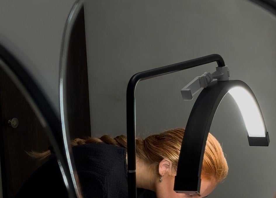 A woman at Coconut & Co, Penrith, England, receiving detailed beauty treatment under a bright light.