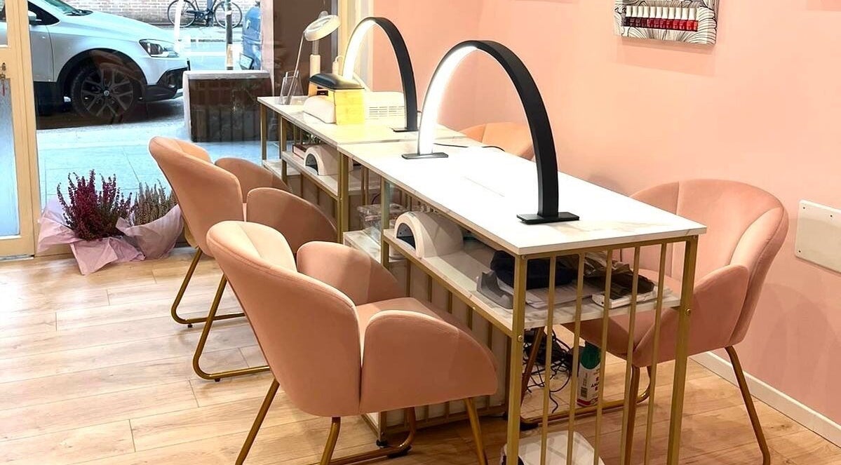 Elegant nail station at Nail It, Bologna, Emilia-romagna, IT, with soft pink chairs and modern lighting.