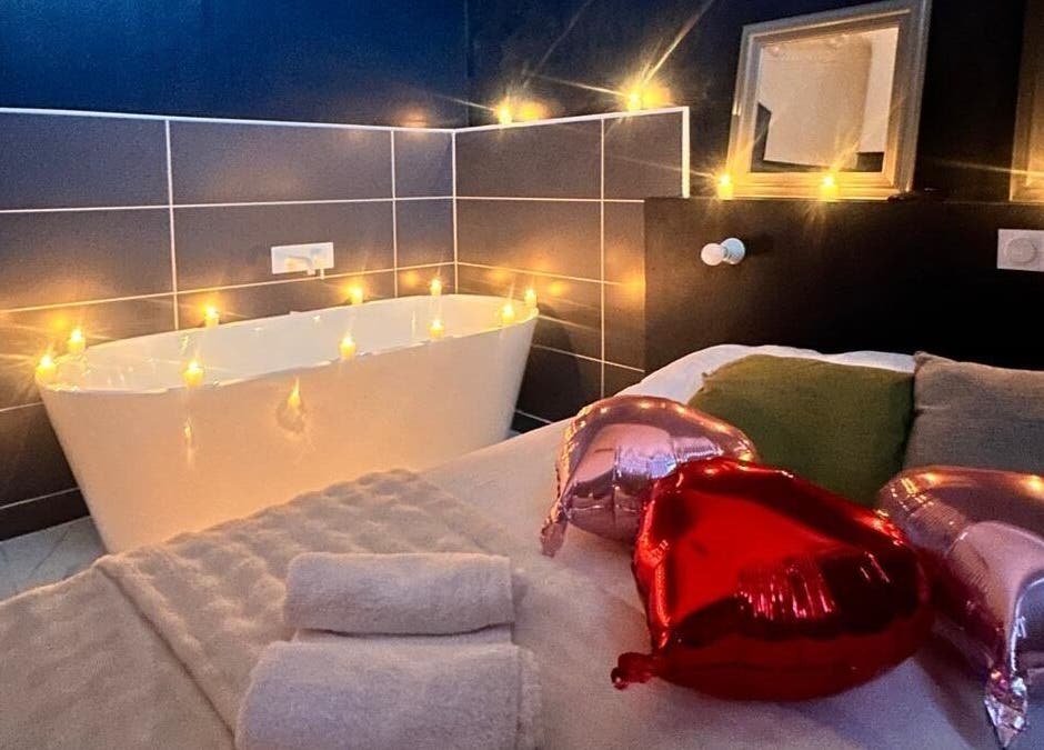 Bain éclairé et lit décoré à Room 47, Tourcoing, Hauts-de-France, FR, offrant une ambiance romantique.