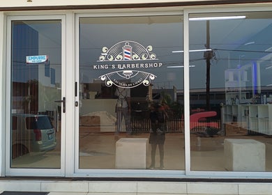 Fachada elegante do King's Barbershop em Maputo, Maputo, MZ, mostrando portas de vidro e o logotipo da barbearia.