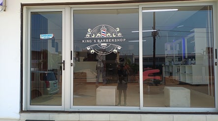 Fachada elegante do King's Barbershop em Maputo, Maputo, MZ, mostrando portas de vidro e o logotipo da barbearia.