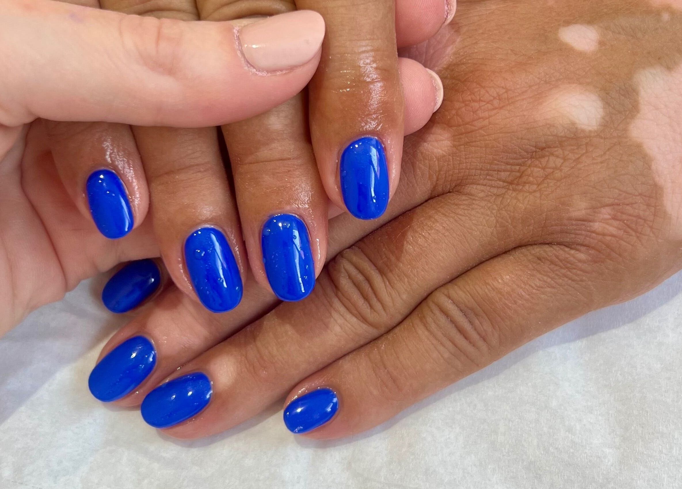 Bright blue manicured nails at Younger Beauty, Preston, England, GB, showcasing expert nail artistry.