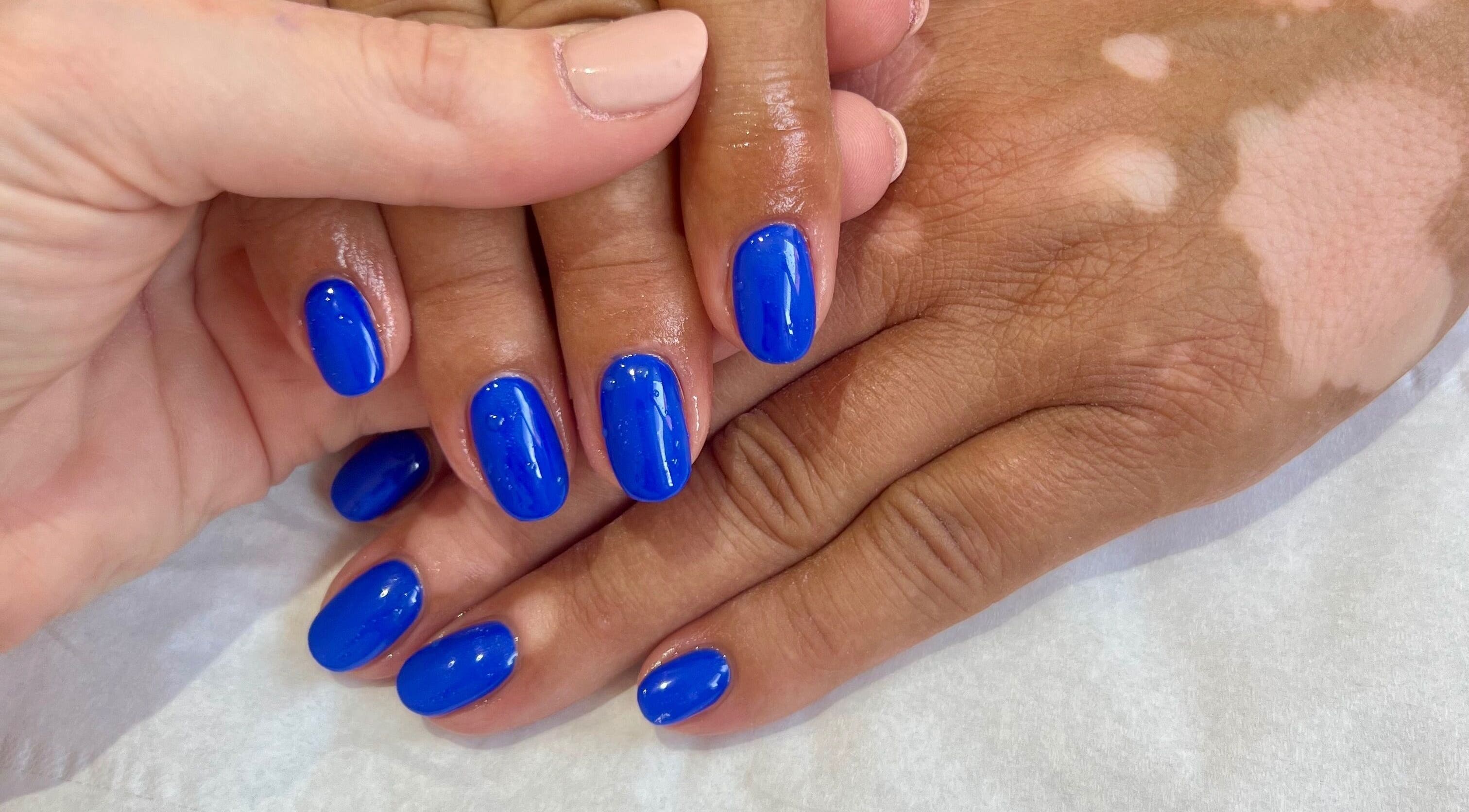 Bright blue manicured nails at Younger Beauty, Preston, England, GB, showcasing expert nail artistry.
