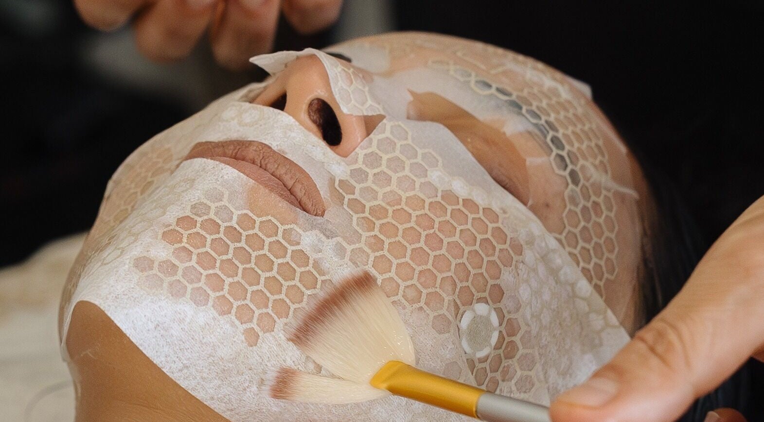 Relaxing facial treatment at Alchemy Spa, Valletta, MT using a honeycomb-pattern mask and soft brush.