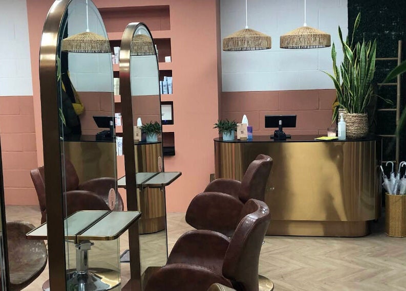 Stylish salon interior at The Tribu Collective in London, England, GB with plush chairs and elegant gold accents.