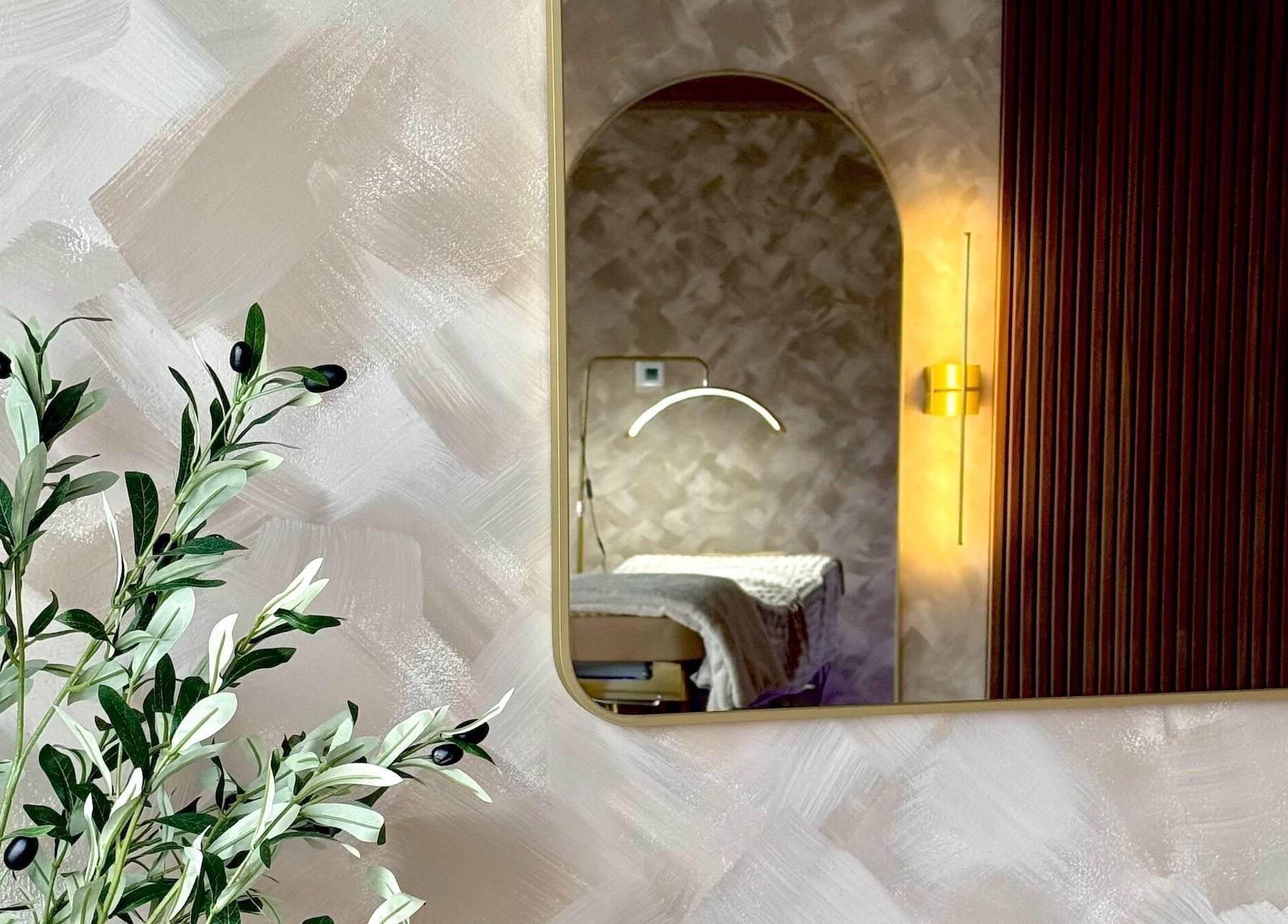 Calming spa room at Garden and Bee, Eatontown, New Jersey, US, featuring a mirror and olive plant.