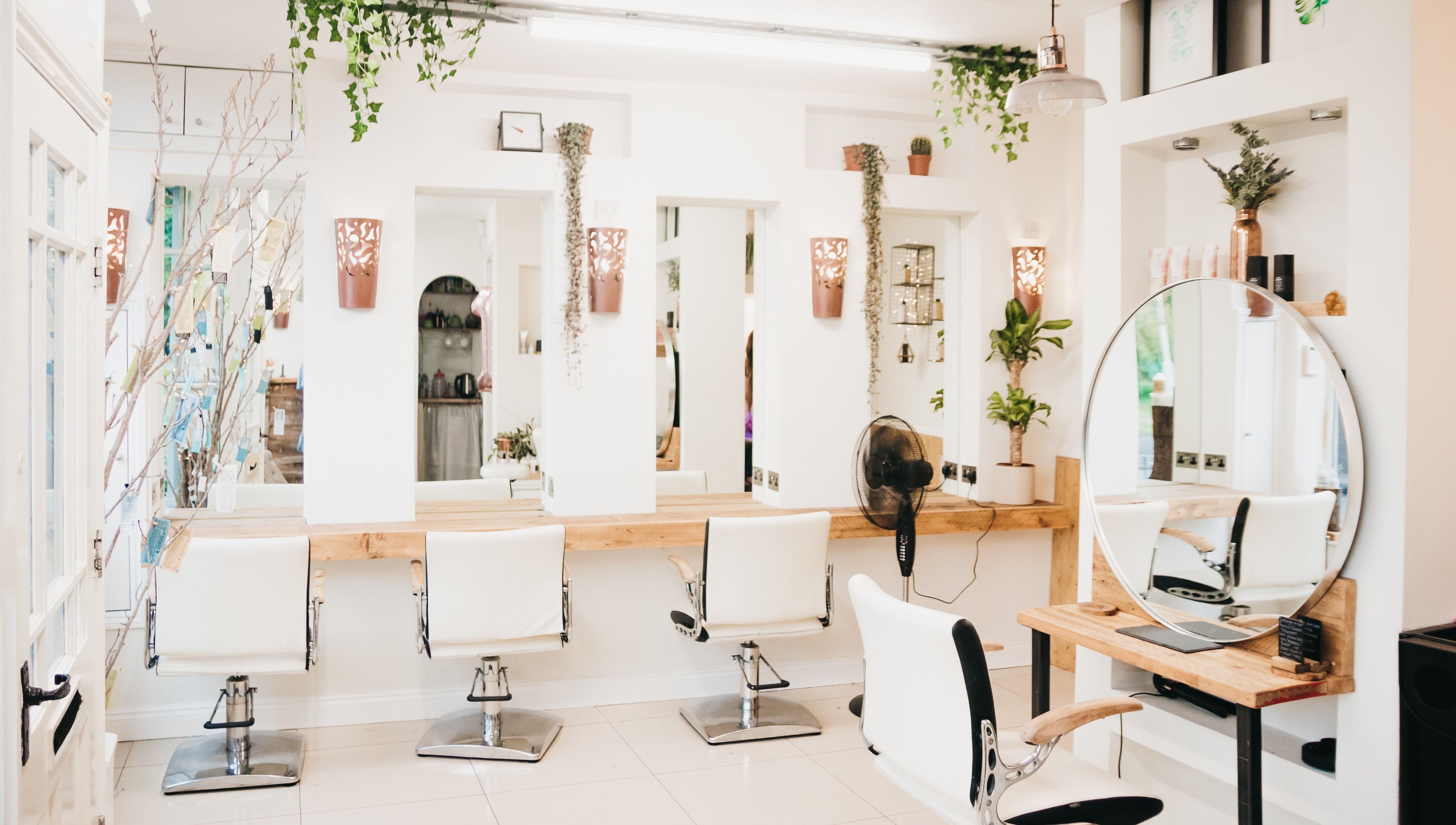 Elegant salon interior at The Root, Harpenden, England, GB featuring modern mirrors and white chairs.