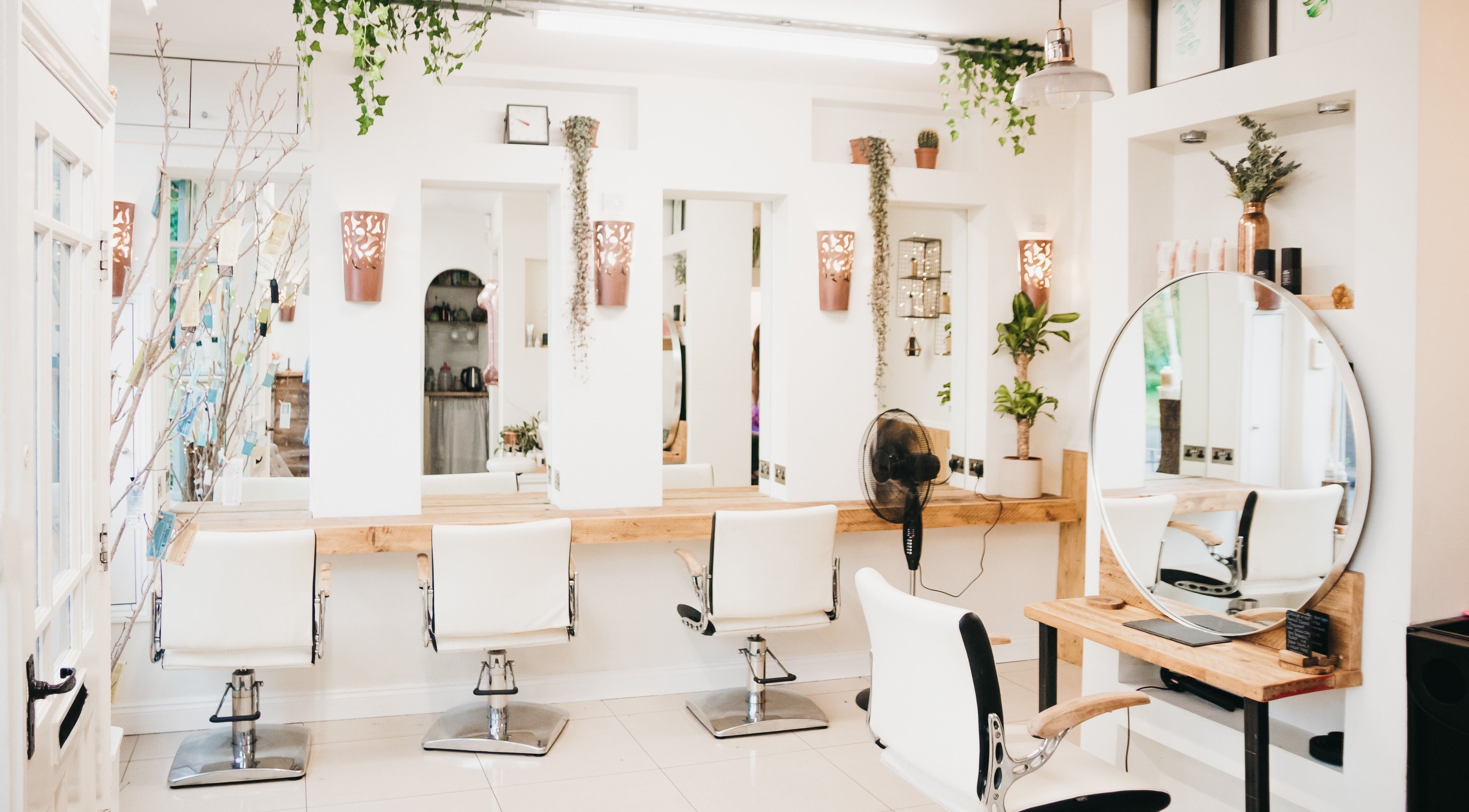 Elegant salon interior at The Root, Harpenden, England, GB featuring modern mirrors and white chairs.