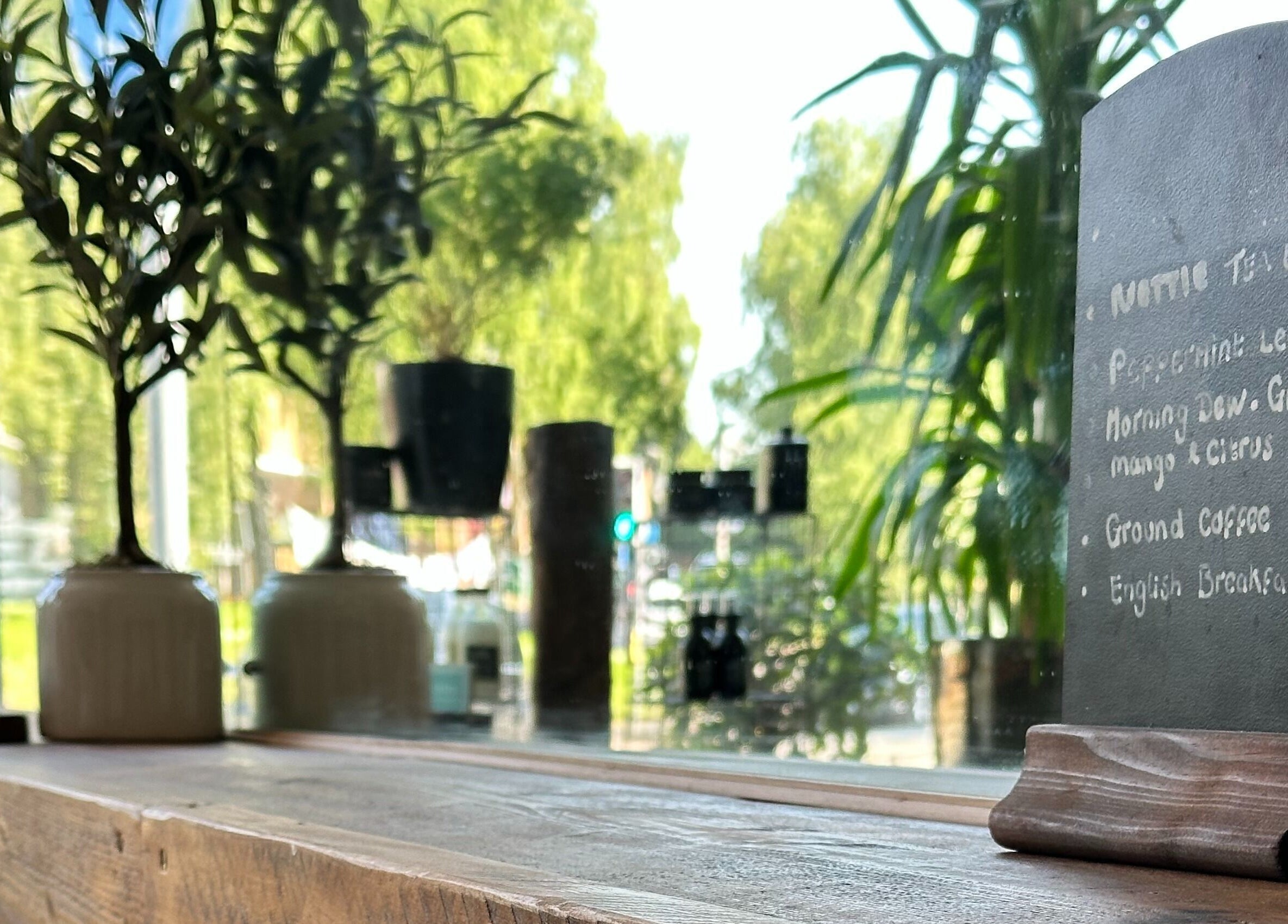 Chalkboard menu and plant at The Root, Harpenden, England, GB, offering a calming and natural ambiance.