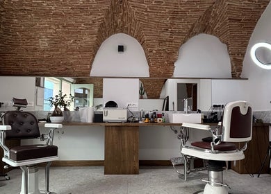 Interno di Barberia a Oristano, Sardegna, IT, con sedie da barbiere e soffitto in mattoni a vista.