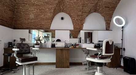 Interno di Barberia a Oristano, Sardegna, IT, con sedie da barbiere e soffitto in mattoni a vista.