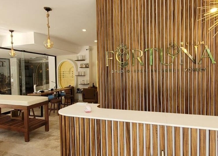 Recepción de Fortuna Studio Spa, Quintana Roo, MX, con diseño elegante de madera y luminarias modernas.