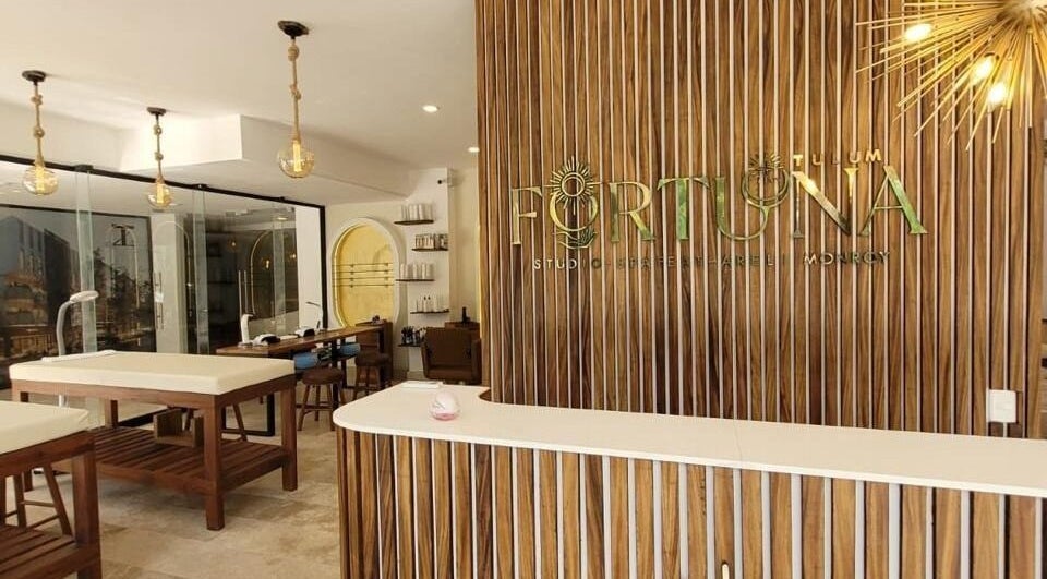 Recepción de Fortuna Studio Spa, Quintana Roo, MX, con diseño elegante de madera y luminarias modernas.