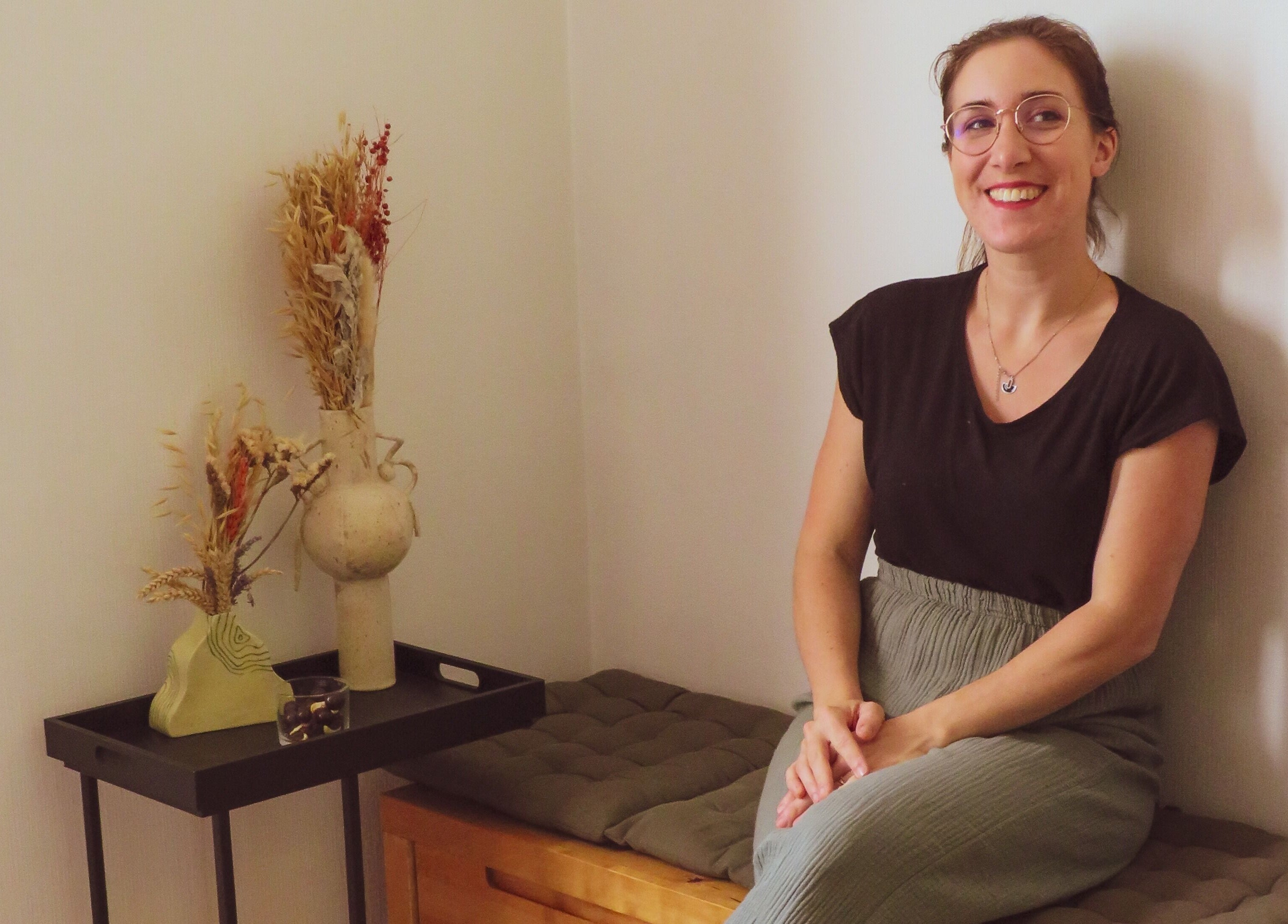 Une femme souriante à Inner Beauty, Dijon, Bourgogne-franche-comté, FR, assise près de décor naturel.