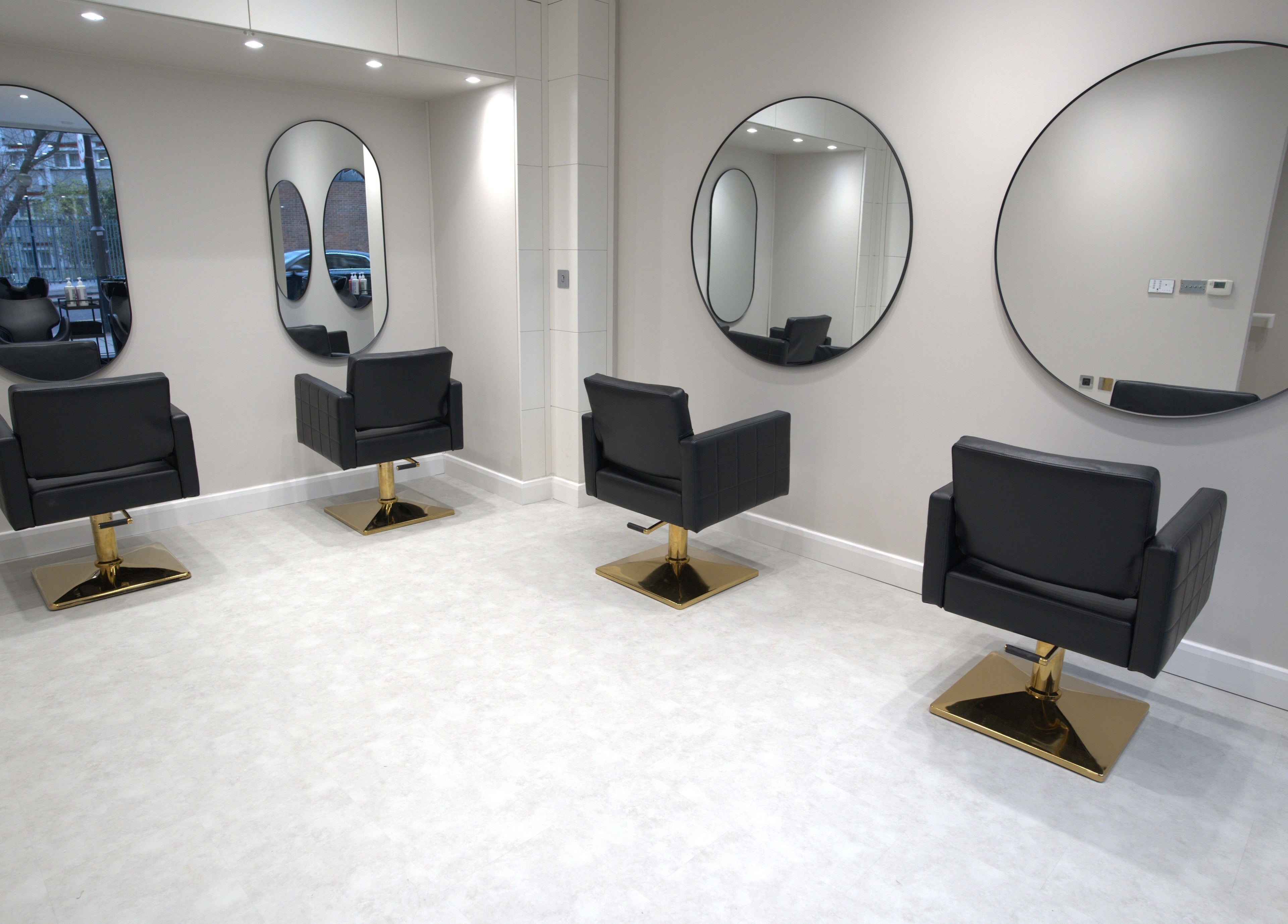 Modern hair styling area at HairNova Angel, London, England, GB with sleek black chairs and large mirrors.