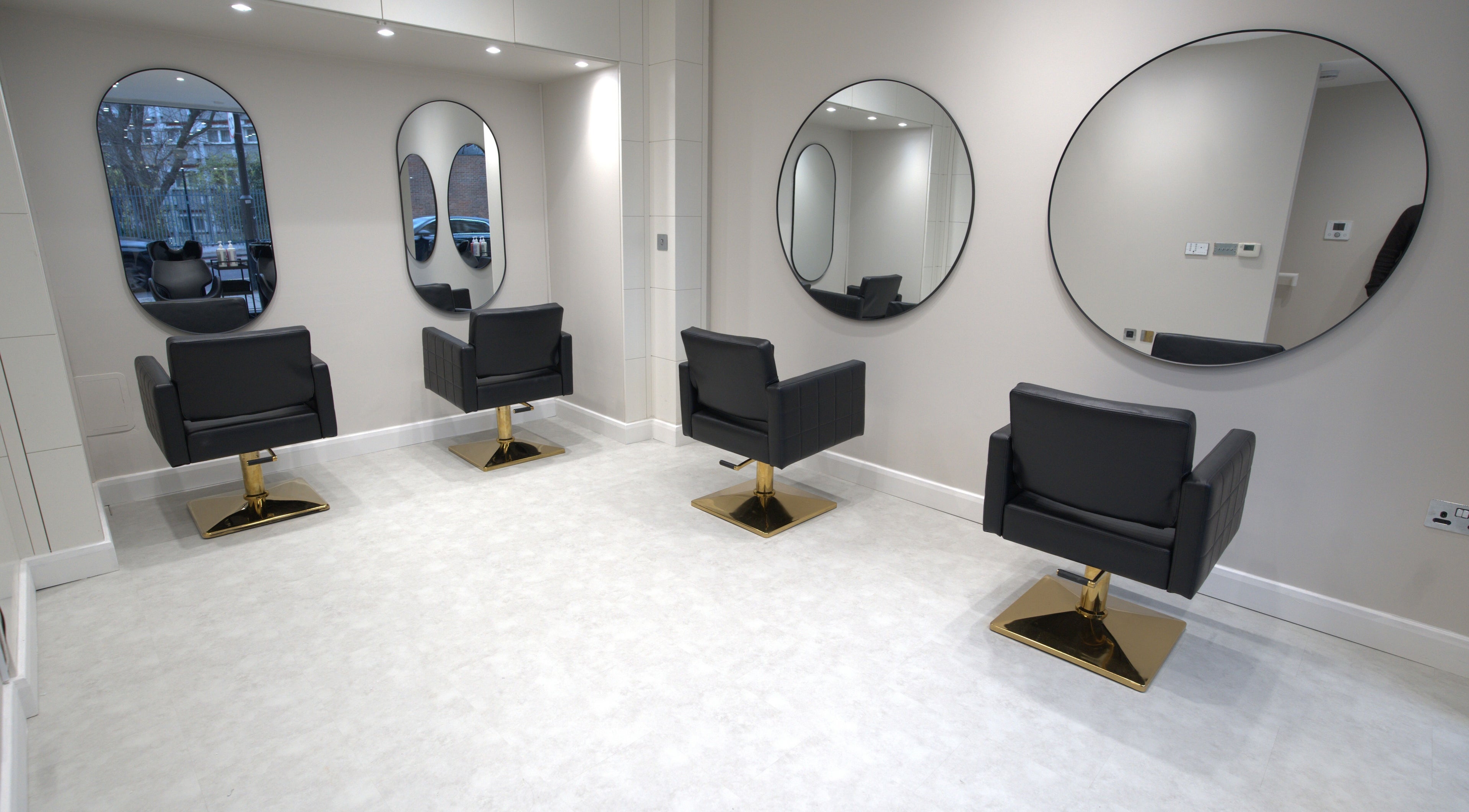 Modern hair styling area at HairNova Angel, London, England, GB with sleek black chairs and large mirrors.