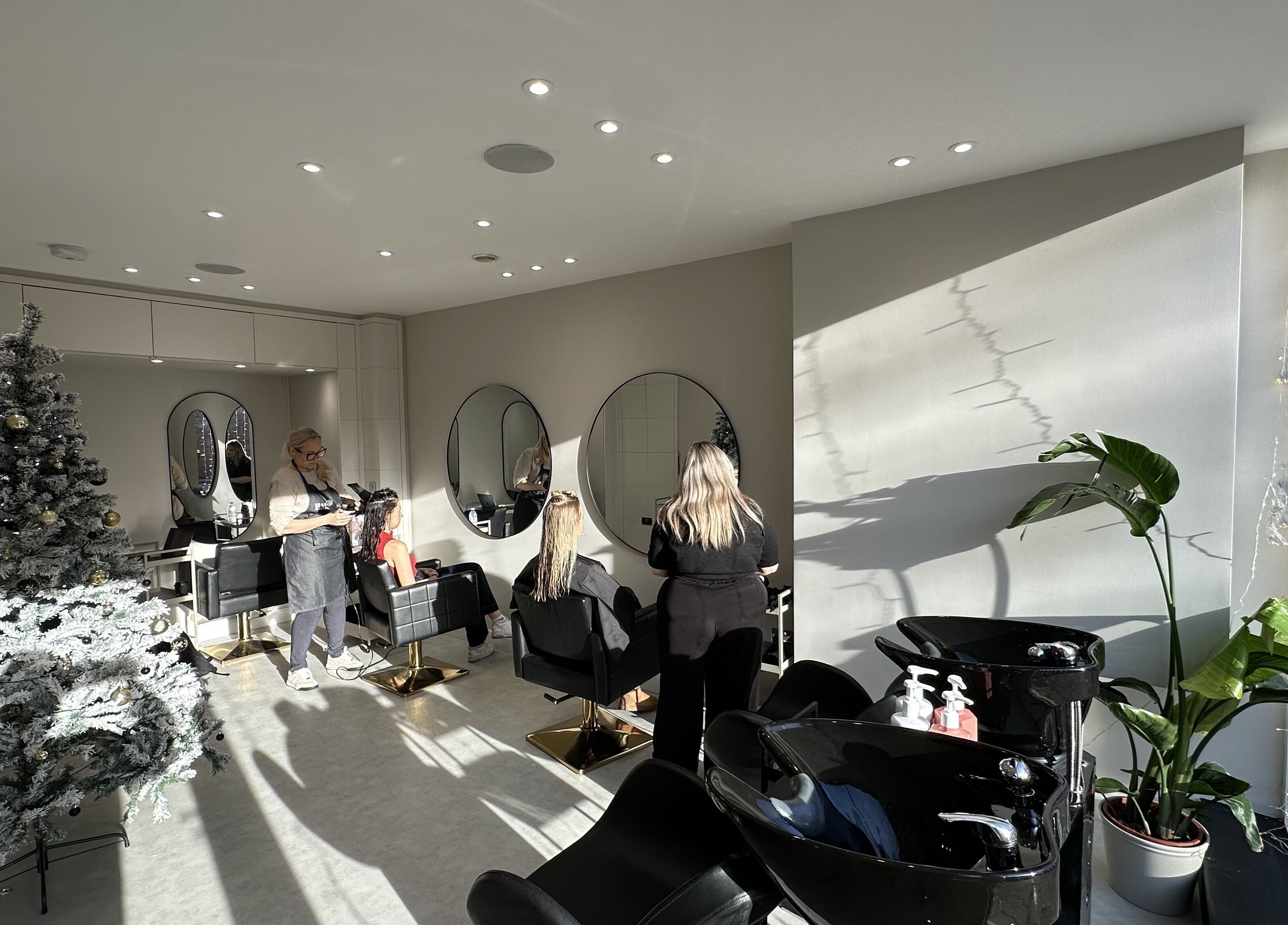 Modern salon at HairNova Angel, London, England, GB, with holiday decor and hairstylist working.