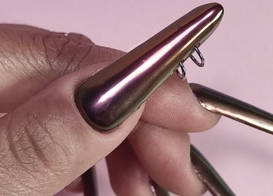Close-up of metallic nails with rings from Lizeth Nailed It, Berlin, Berlin, DE.