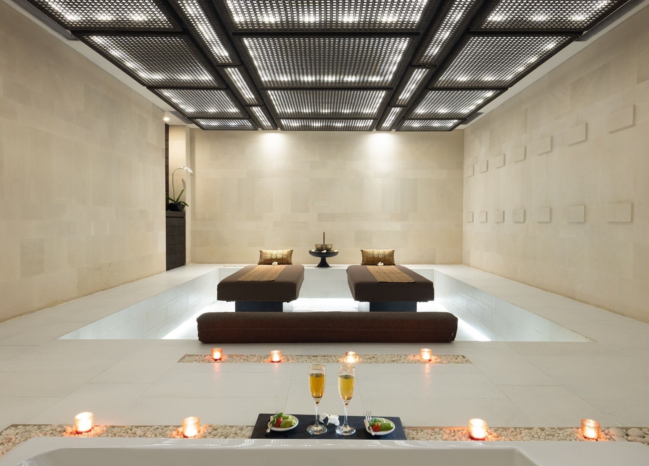 Luxurious massage beds at eqUALIZE Spa in Kuta Utara, Bali, ID, surrounded by candles for relaxation.