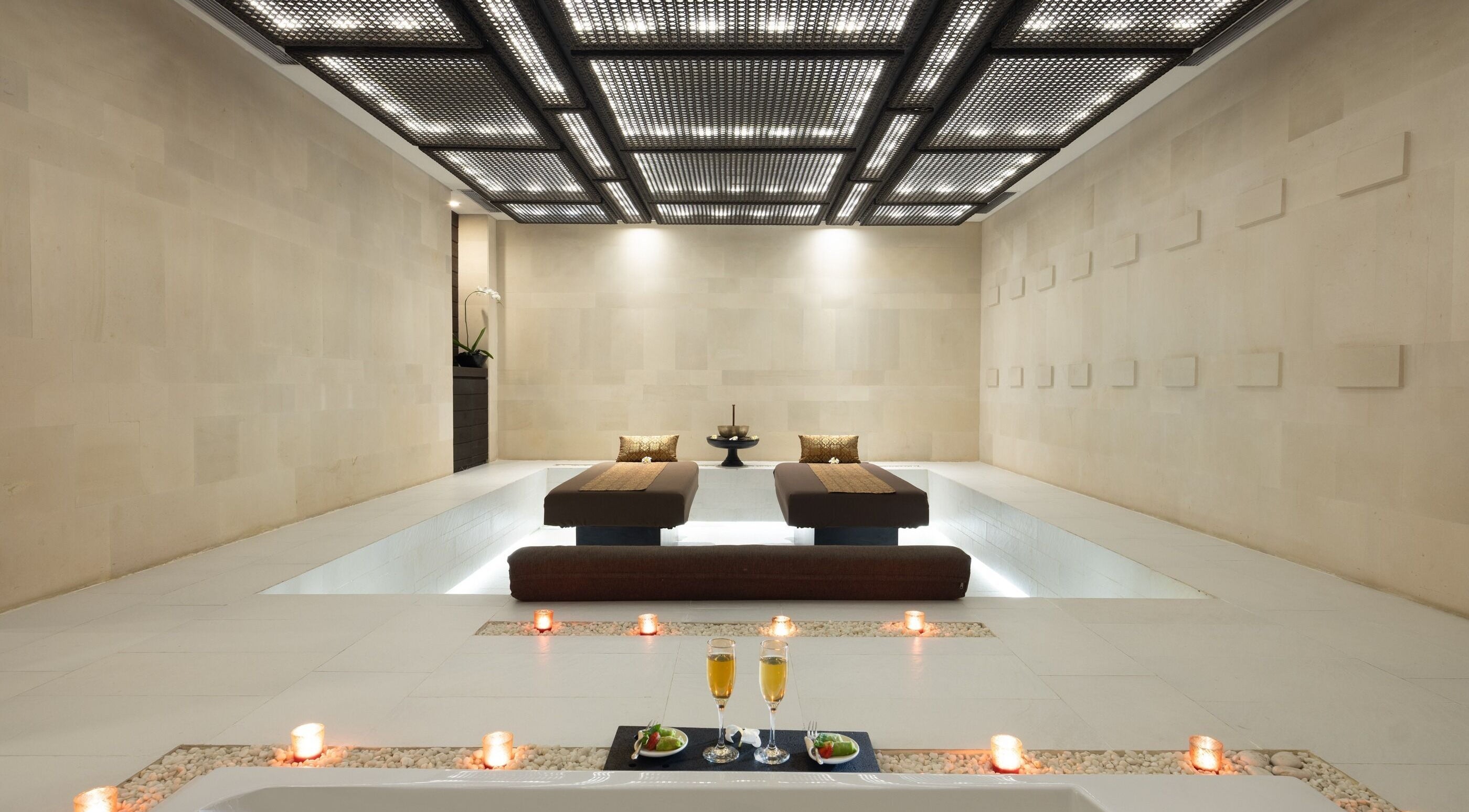 Luxurious massage beds at eqUALIZE Spa in Kuta Utara, Bali, ID, surrounded by candles for relaxation.