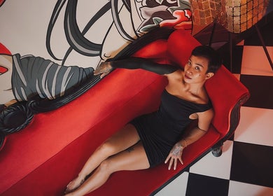 Stylish woman on red sofa at RedDoors, Bali, Bali, ID with vibrant wall art and checkered floor.