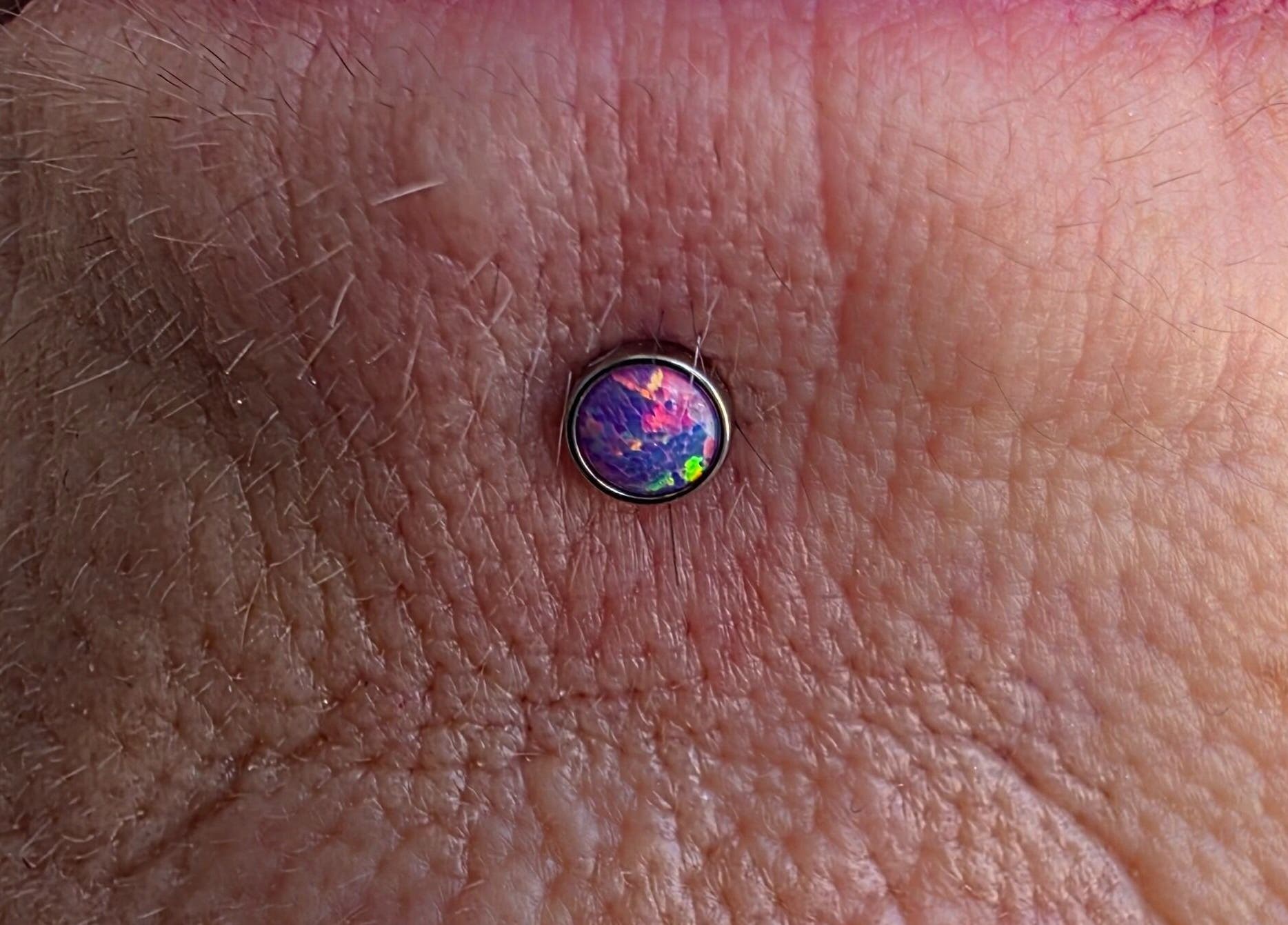 Unique opal body piercing at Sharp Art Body Piercing, Langport, England, GB showcasing intricate design.