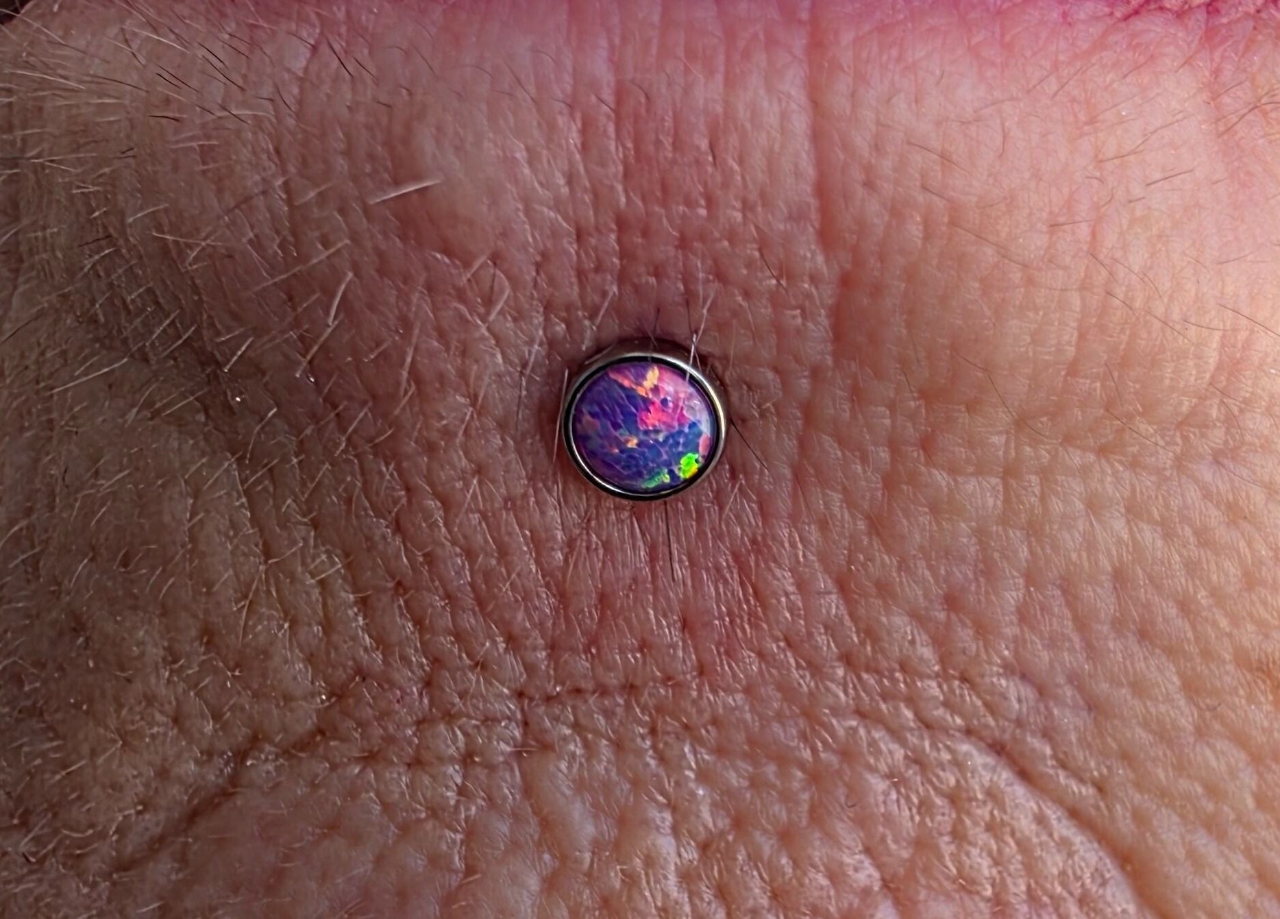 Unique opal body piercing at Sharp Art Body Piercing, Langport, England, GB showcasing intricate design.