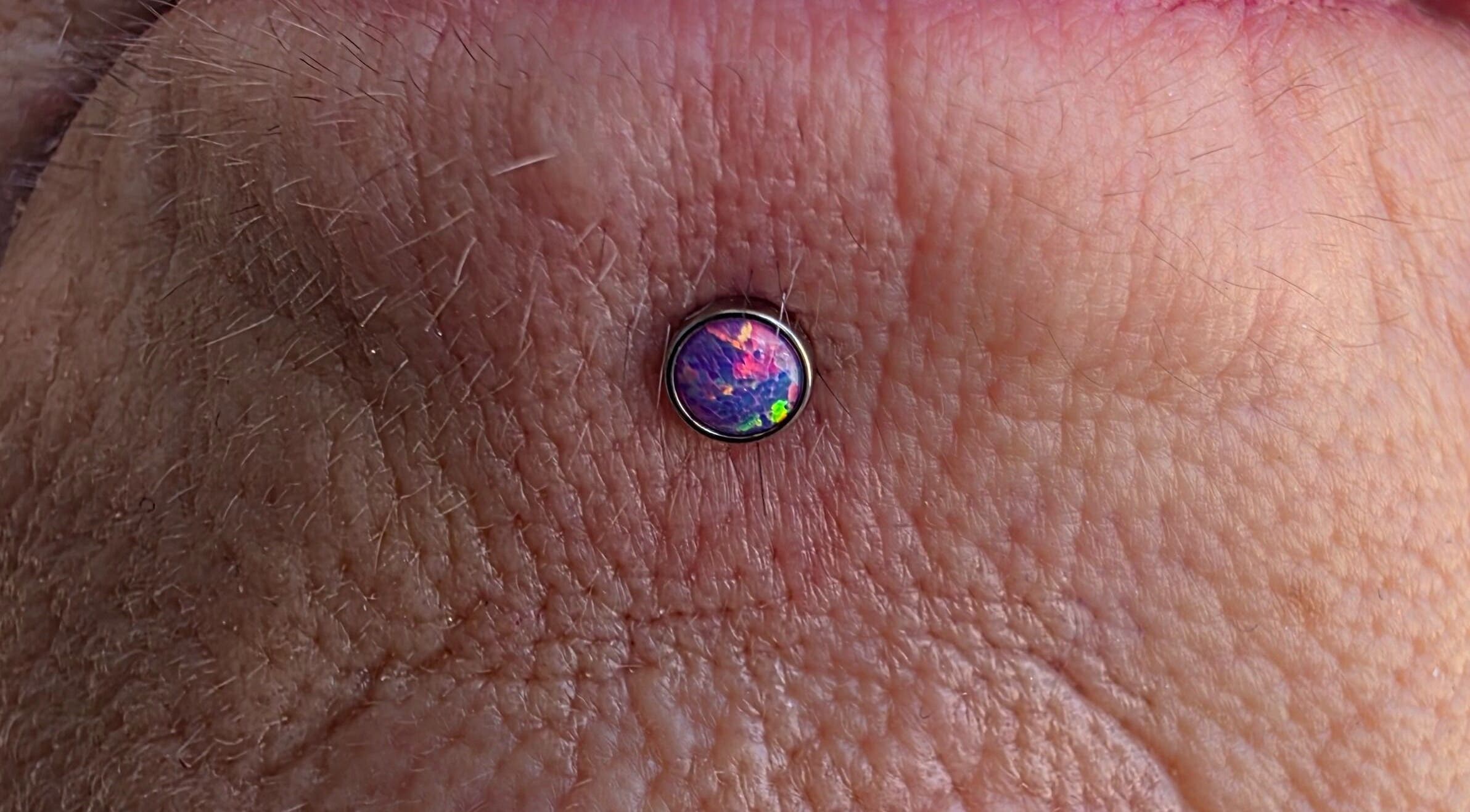 Unique opal body piercing at Sharp Art Body Piercing, Langport, England, GB showcasing intricate design.