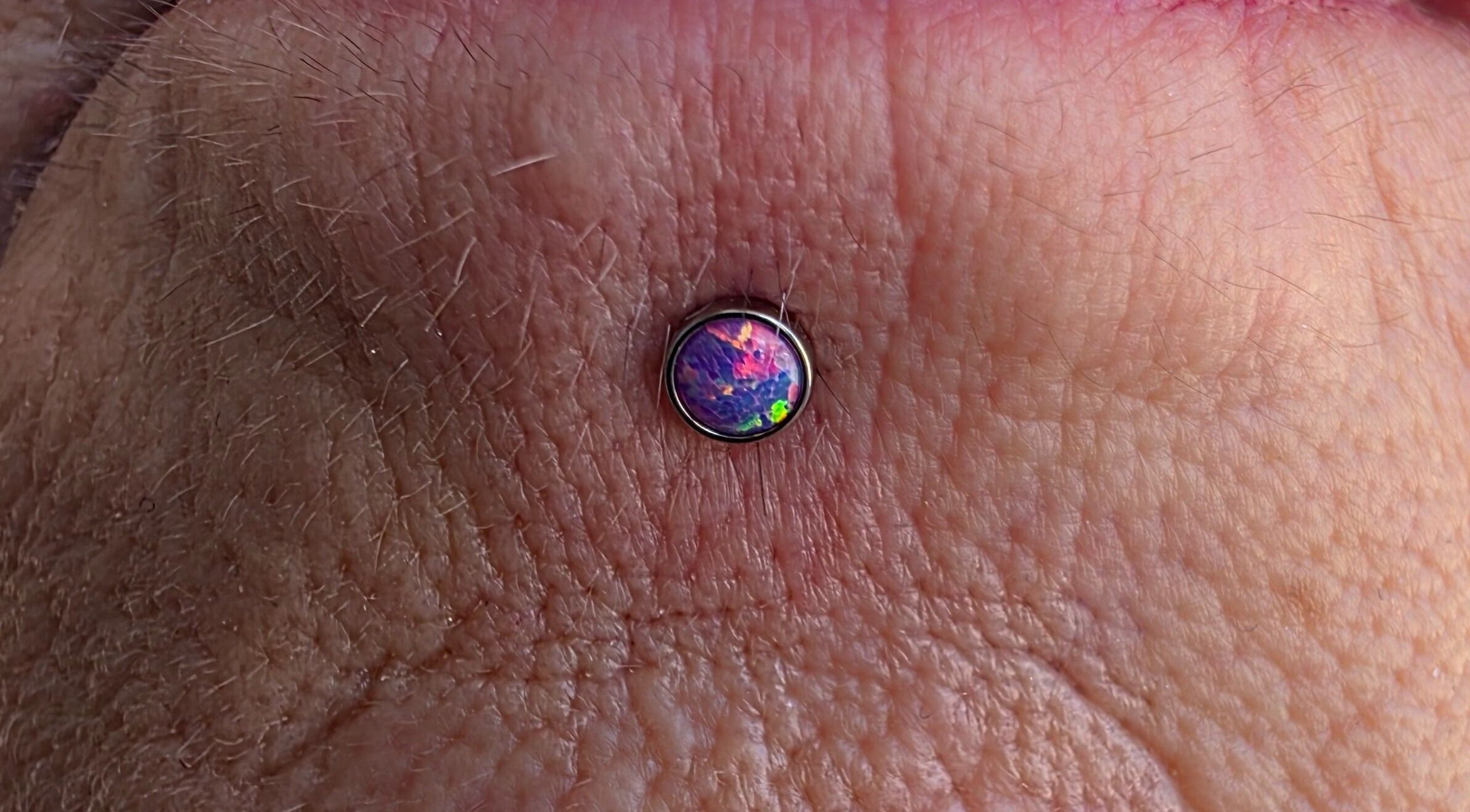 Unique opal body piercing at Sharp Art Body Piercing, Langport, England, GB showcasing intricate design.