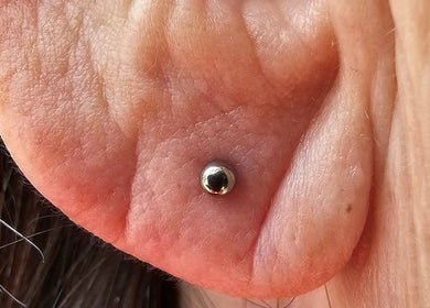 Polished ear lobe piercing at Sharp Art Body Piercing, Langport, England, GB showcasing precision and style.