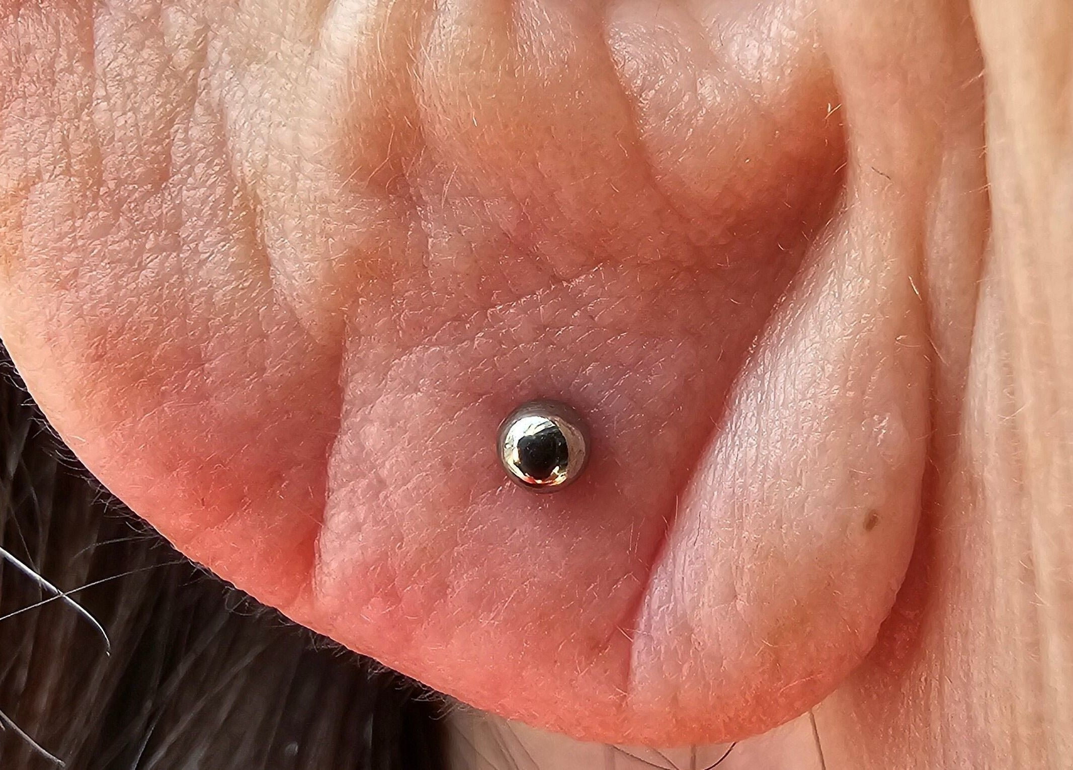 Polished ear lobe piercing at Sharp Art Body Piercing, Langport, England, GB showcasing precision and style.