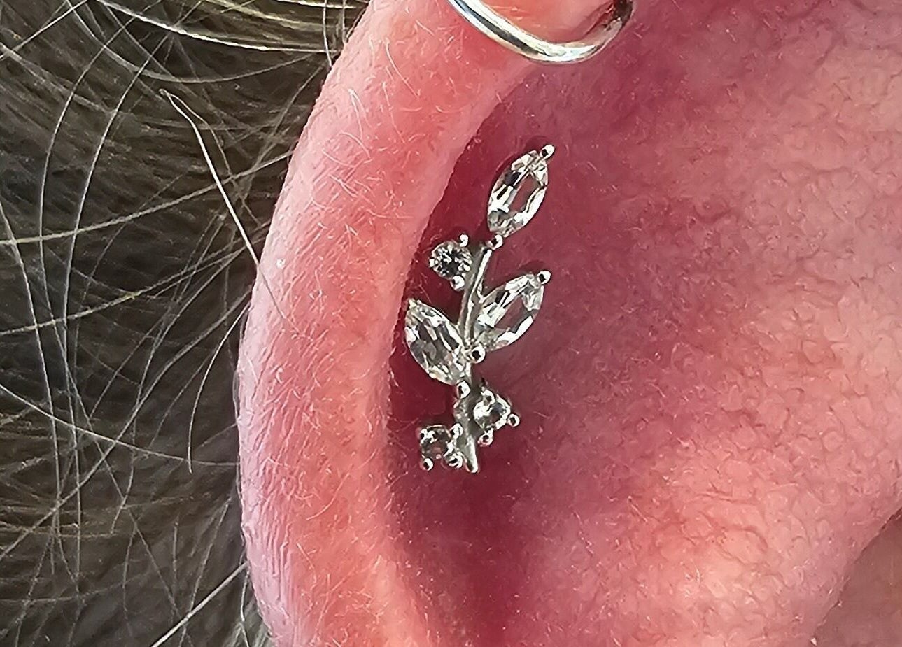 Elegant ear piercing at Sharp Art Body Piercing, Langport, England, GB, featuring a unique gemstone design.