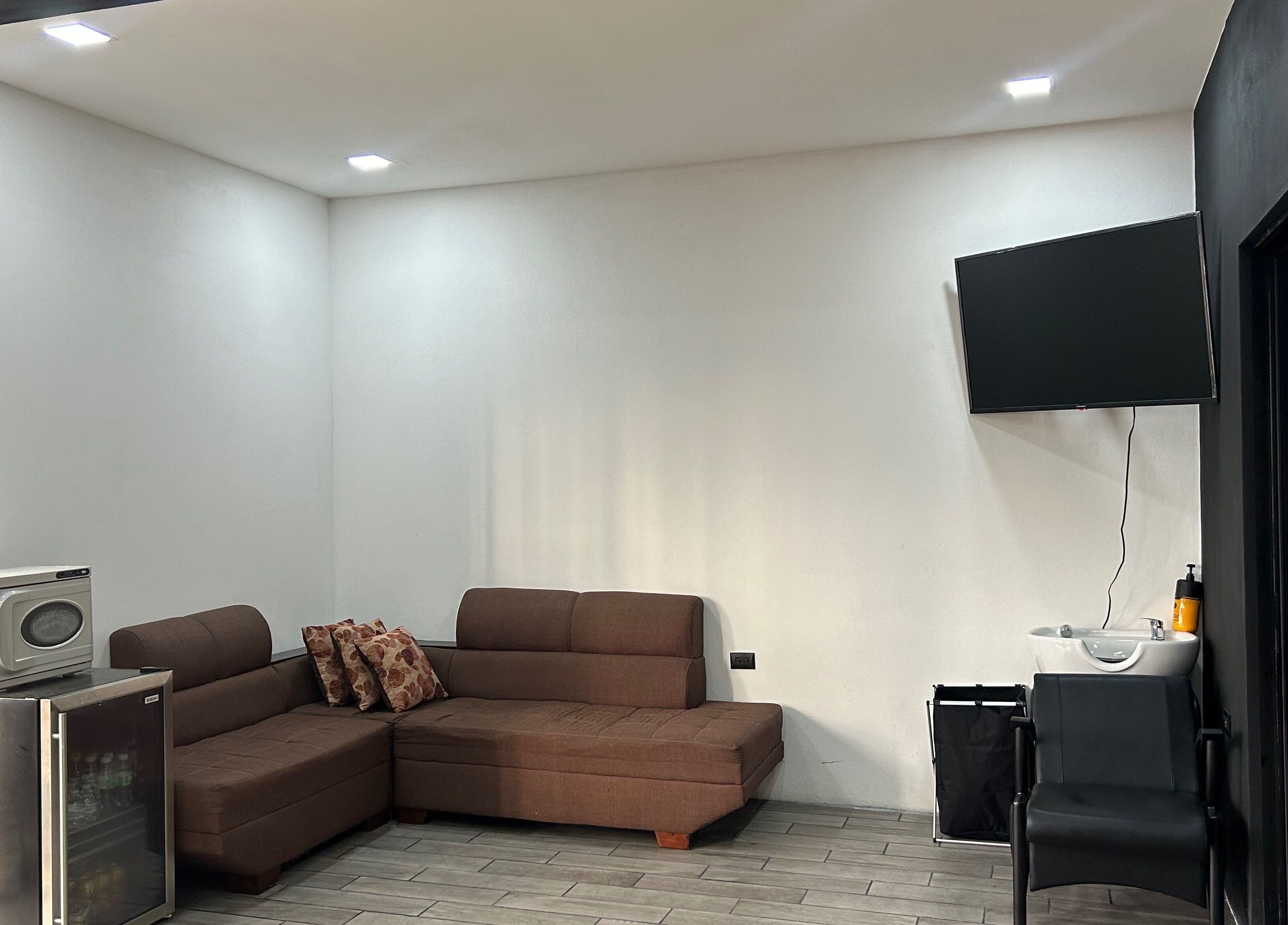 Zona de espera en Imperio Barbero, Grecia, Provincia De Alajuela, CR con sofá y televisor moderno.