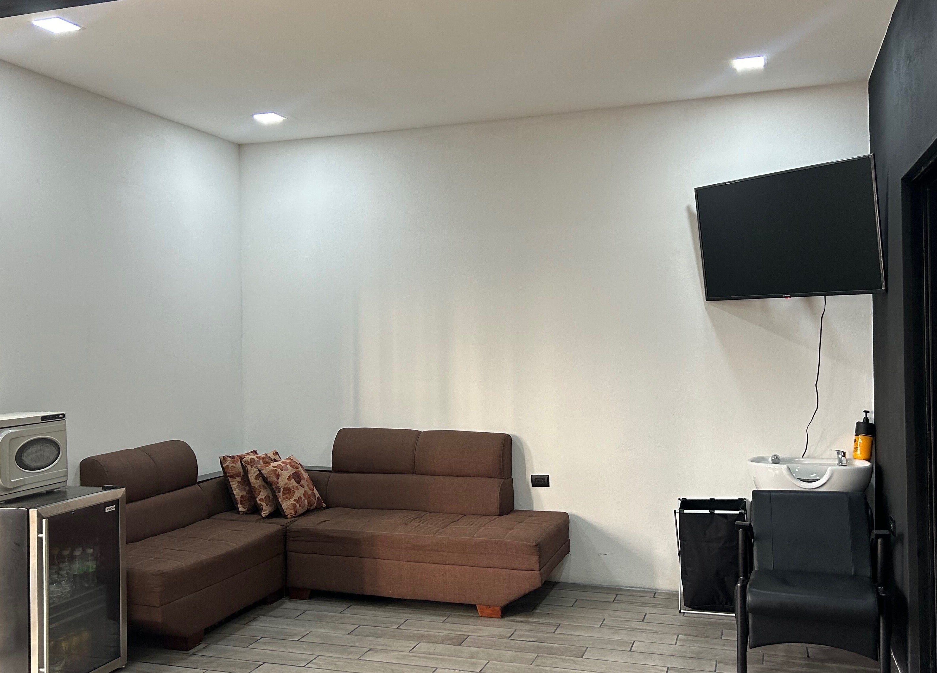 Zona de espera en Imperio Barbero, Grecia, Provincia De Alajuela, CR con sofá y televisor moderno.