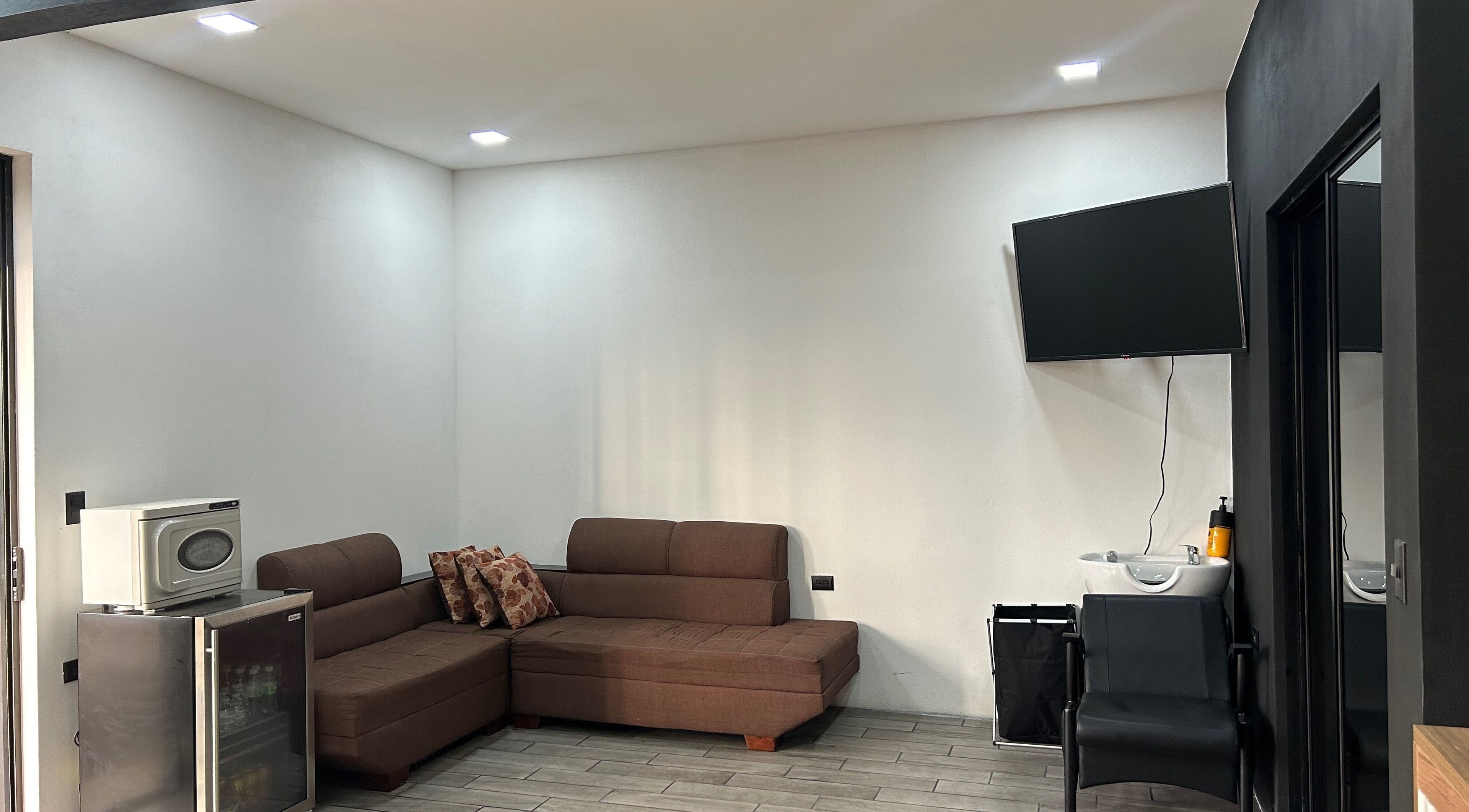 Zona de espera en Imperio Barbero, Grecia, Provincia De Alajuela, CR con sofá y televisor moderno.