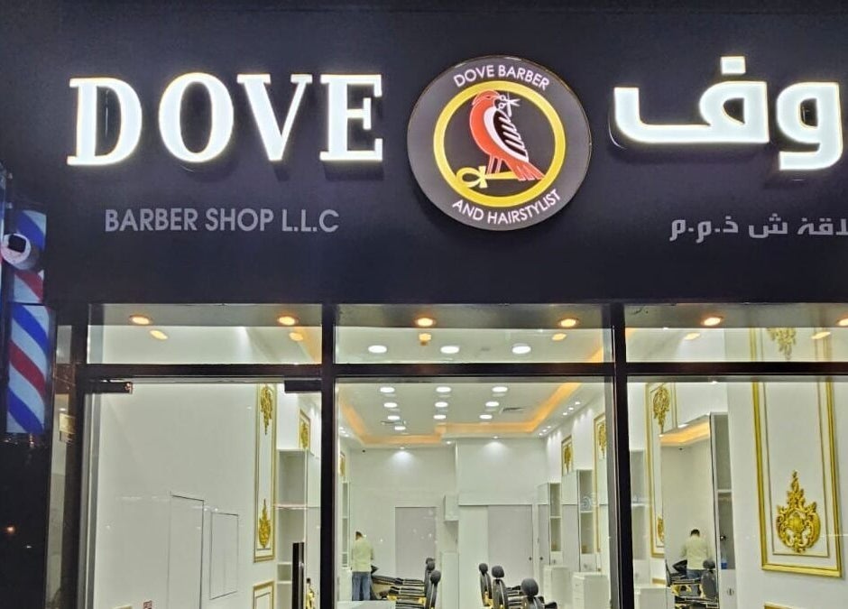 Front entrance of Dove Barbershop in Dubai, Dubai, AE, illuminated at night, showcasing modern design.
