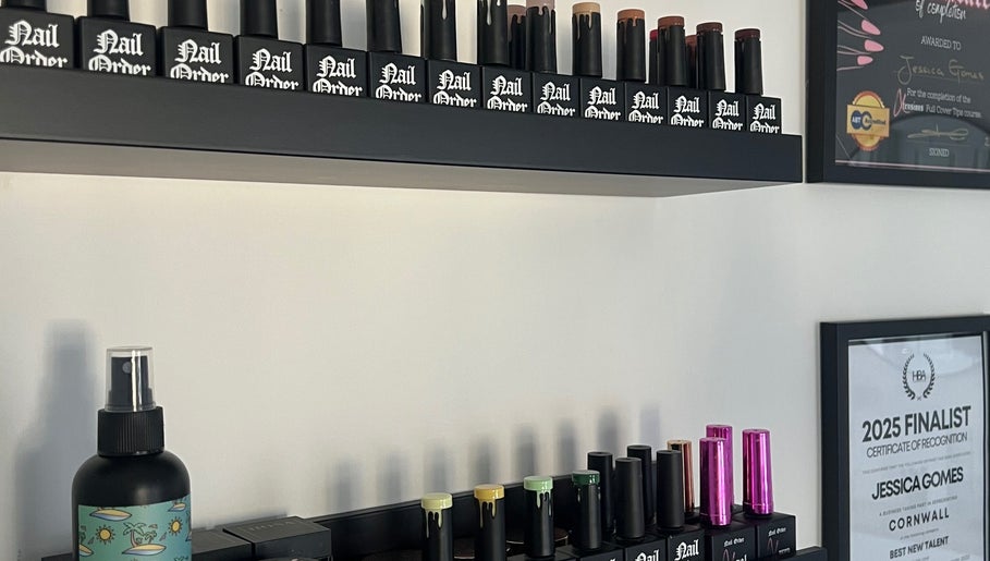 Nail polish collection on shelves at Nails By Jess, St Austell, England, GB. Certification awards displayed.